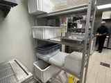 un homme debout dans une cuisine, à côté d'une étagère