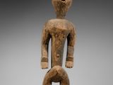 une statue en bois d'un homme avec un chapeau sur la tête