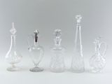 several glass bottles and vases are lined up on a white surface