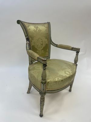 a green upholstered chair with a gold upholstered back and arms