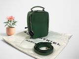 le petit sac vert est posé sur une nappe blanche, à côté d'une fleur rose