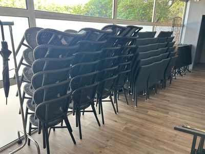 des rangées de chaises noires dans une pièce dotée de grandes fenêtres et d'un parquet