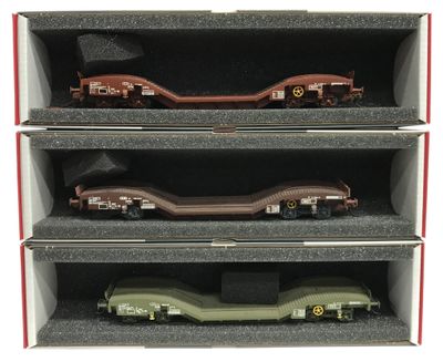 trois wagons de train miniature se trouvent dans une boîte posée sur une surface blanche