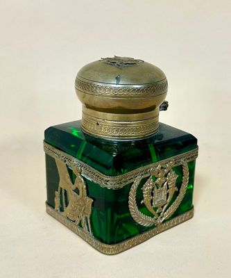 a green glass bottle with a gold lid on a white surface