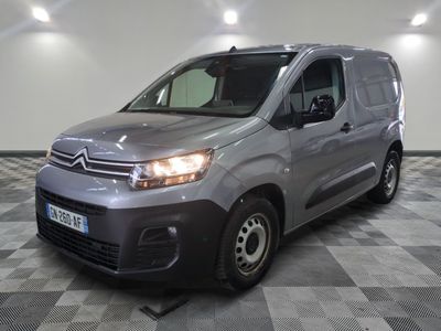 La camionnette argentée est garée dans une grande pièce au sol carrelé en damier.