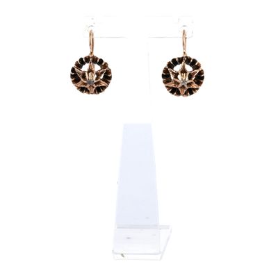une paire de boucles d'oreilles noires et dorées présentée sur un présentoir transparent