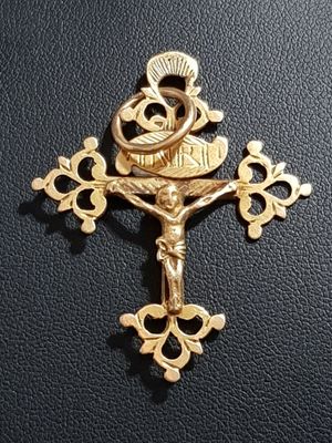 gold plated crucift with a cross on a black leather surface
