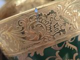 a close up of a bowl with gold and green designs on it
