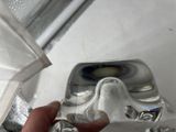 a hand that is holding a clear object in front of a faucet