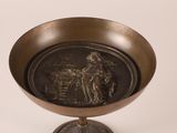 a bronze bowl with a picture of a man riding a horse on it