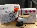 a white sewing machine sitting on a table next to a box