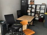 a room with a desk, chairs, and a television