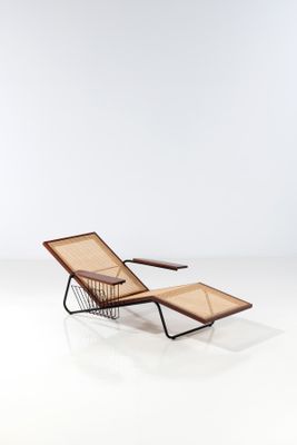 the lounge chair is made of rattan and has a wooden frame
