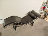 a black leather chaise lounger in the corner of a room
