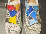 une paire de chaussures pour enfants ornées de motifs colorés, posées sur une surface noire