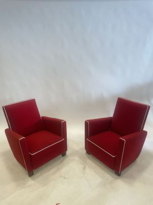 pair of red leather lounge chairs with white piping on the arms