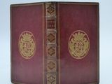 an old book with a red cover and a gold emblem on it