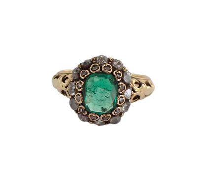 gros plan d'une bague avec une pierre verte entourée de diamants