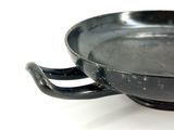 a black bowl with a handle on a white surface