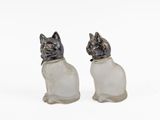 two glass cats sitting next to each other on a white surface
