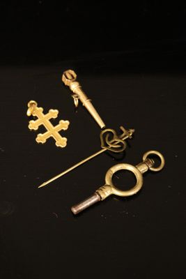 three gold keys and a keychain on a black surface