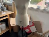 a mannequin on a stand in a room with a lot of boxes on the floor