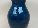 a blue vase that is sitting on a white surface