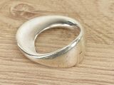 silver ring on a wooden table with a white diamond in the middle