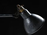 close up of a black lamp on a black wall with a black background