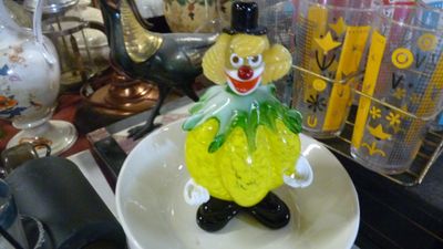 une figurine en verre représentant un clown, posée sur une assiette
