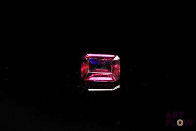 a close up of a pink stone on a black surface