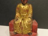 a gold statue of a man sitting on a red chair