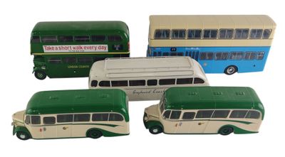 quatre petits bus jouets posés les uns à côté des autres sur une surface blanche