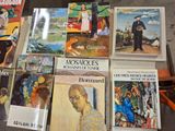 several books are sitting on a table in front of a pile of other books