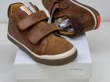 brown leather baby shoes with velcro straps on top of a white box