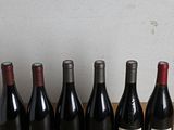 several bottles of wine are lined up on a wooden table