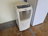 un petit climatiseur posé à côté d'un réfrigérateur