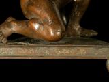 a bronze statue of a man kneeling on a table