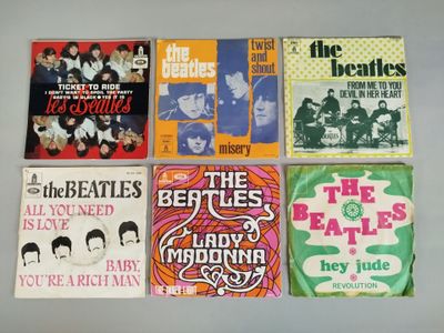 Plusieurs albums des Beatles sont disposés sur une surface blanche