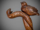 two wooden birds perched on a tree branch on a gray background
