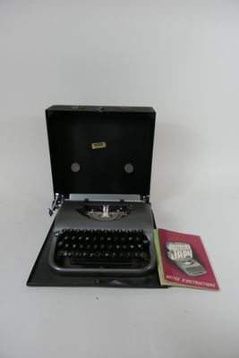 une vieille machine à écrire posée sur une table, à côté d'un livre