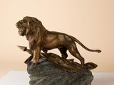 bronze statue of a lion on a rock on a white surface