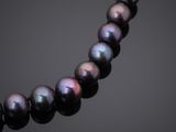 a black pearl necklace on a black surface