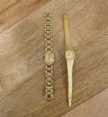 two gold watches on a wooden surface with a wooden floor
