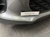 the front bumper of a silver car with a sticker on it