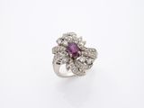 gros plan d'une bague en diamant et rubis sur une surface blanche