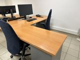 a desk with two computers and a fan in the corner