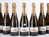 six bouteilles de champagne alignées sur une surface blanche