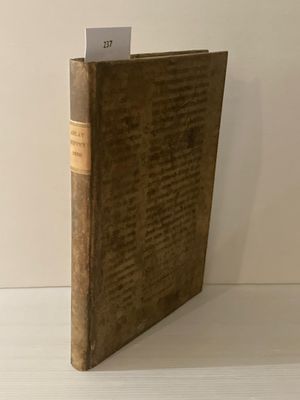 un vieux livre posé sur une table à côté d'un mur blanc