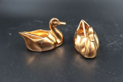 paire de figurines de cygnes plaquées or sur un fond noir